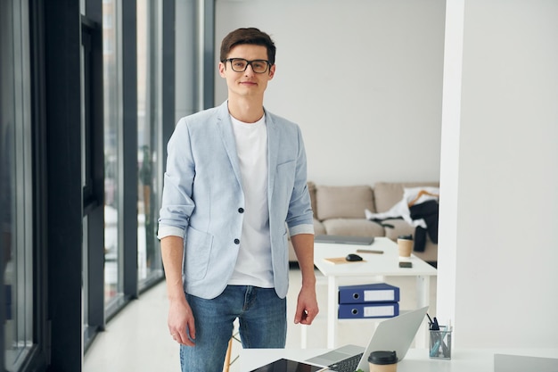 Junge Männer mit Brille und formeller Kleidung stehen im Büro