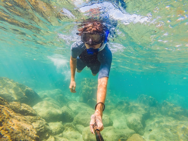 Junge Männer schnorcheln beim Erkunden der Unterwasserkorallenrifflandschaft im tiefblauen Ozean mit bunten Fischen und Meereslebewesen