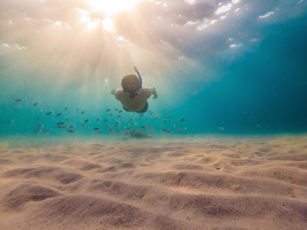 Junge Männer schnorcheln beim Erkunden der Unterwasserkorallenrifflandschaft im tiefblauen Ozean mit bunten Fischen und Meereslebewesen