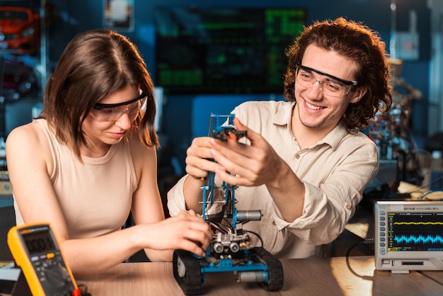 Junge Männer und Frauen mit Schutzbrille machen Experimente zur Robotik in einem Laborroboter