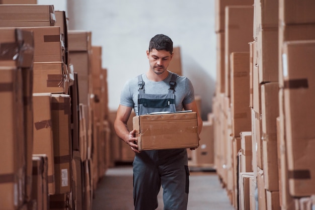 Junge männliche Arbeiter in Uniform sind im Lager mit Box in den Händen.