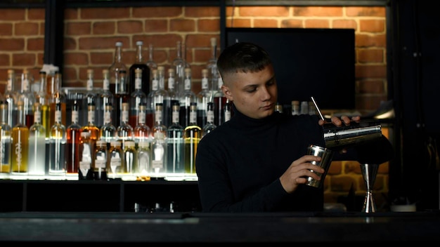 Junge männliche Barkeeper mit Shaker für die Alkoholgetränke Vorbereitung Aktion Konzept der Party in der Nacht