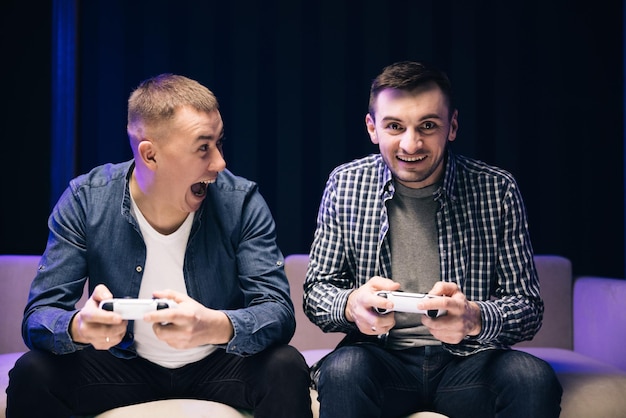 Foto junge männliche freunde, die zu hause ein spiel mit joystick spielen kaukasische männer, die fernsehen, um gemeinsam videospiele zu spielen