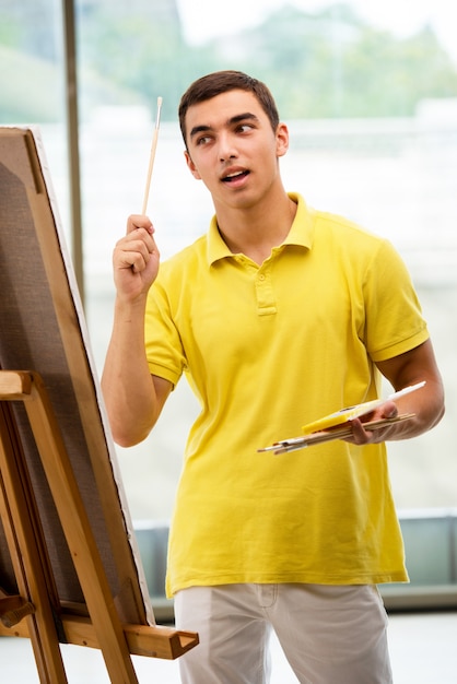 Junge männliche Künstlerzeichnungsbilder im hellen Studio