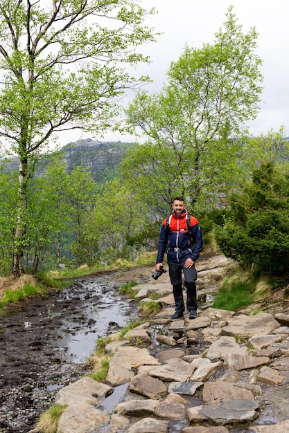 Junge männliche Touristen wandern auf dem Weg zum Preikestolen an einem kleinen Fluss, umgeben von Bäumen