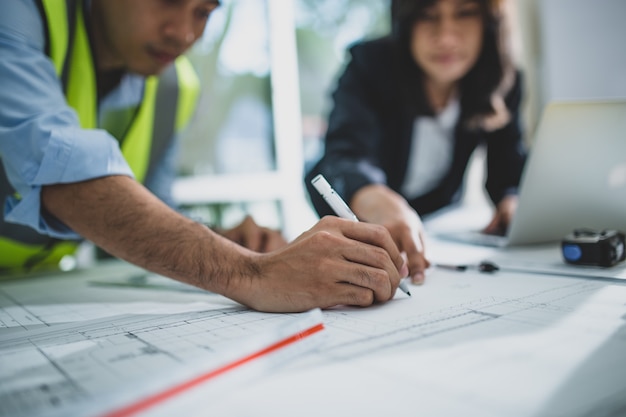 Foto junge männliche und weibliche architektenkollegen zeichnen grafische planung des innenarchitekturprojekts, das mit talentiertem lehrer zusammenarbeitet, der ratschläge gibt und fehler während der trainingsstunde korrigiert