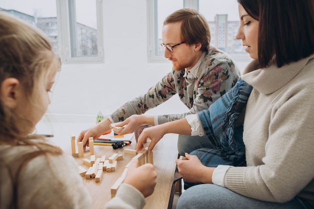 Junge Mama und Papa spielen Lernspiele mit Kindern