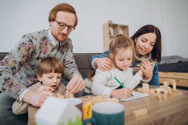 Junge Mama und Papa spielen Lernspiele mit Kindern