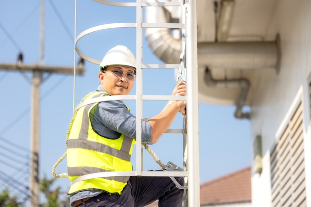 Junge Mann Arbeiter oder Ingenieur klettern Leiter.