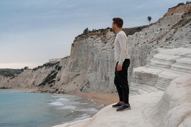 Foto junge mann bewundert die weißen kalksteinklippen der scala dei turchi agrigento sizilien italien