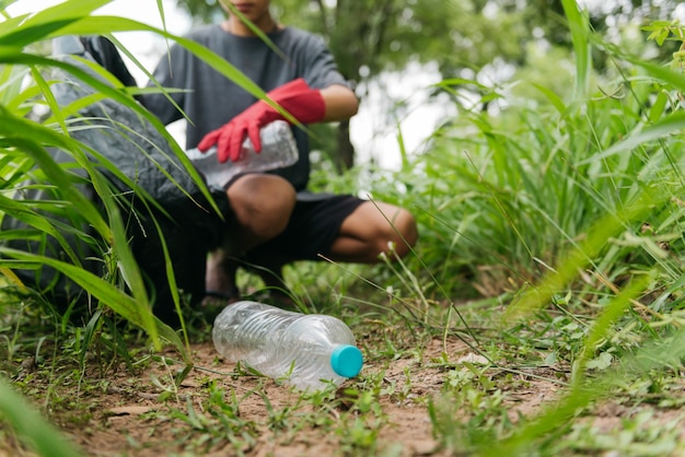 Junge Mann Hand heben Plastikflasche im Wald auf. Naturschutz- und Umweltkonzept.