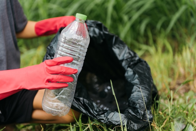 Junge Mann Hand heben Plastikflasche im Wald auf. Naturschutz- und Umweltkonzept.