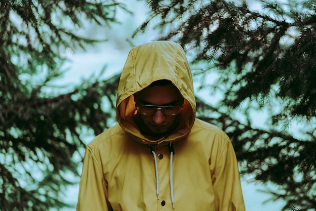 Junge Mann mit Brille am Kiefernbaum