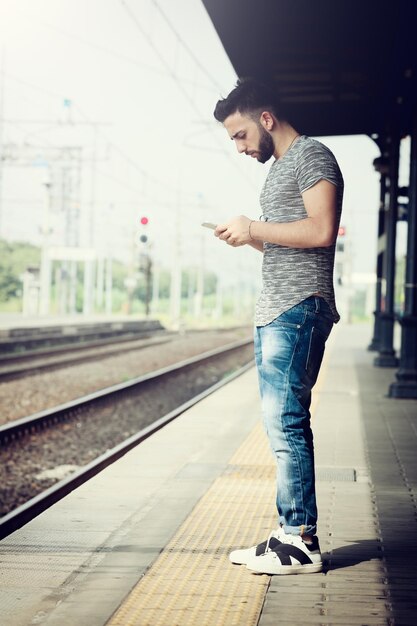 Foto junge mann mit einem smartphone am bahnhof