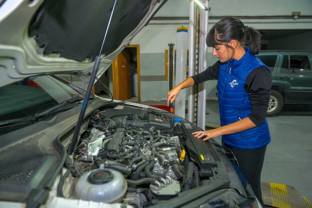 Junge Mechanikerin arbeitet an der Reparatur eines Automotors