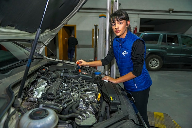 Junge Mechanikerin arbeitet an der Reparatur eines Automotors