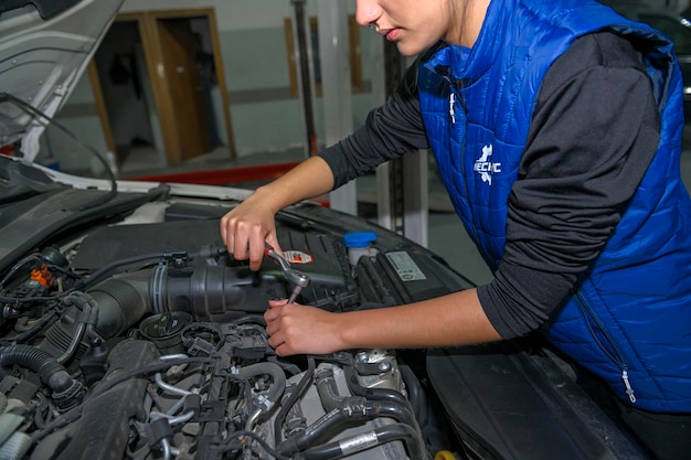 Junge Mechanikerin arbeitet an der Reparatur eines Automotors