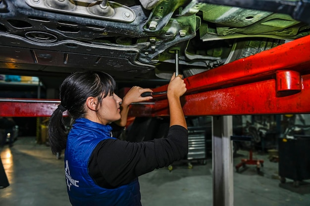 Junge Mechanikerin arbeitet an der Reparatur eines Automotors