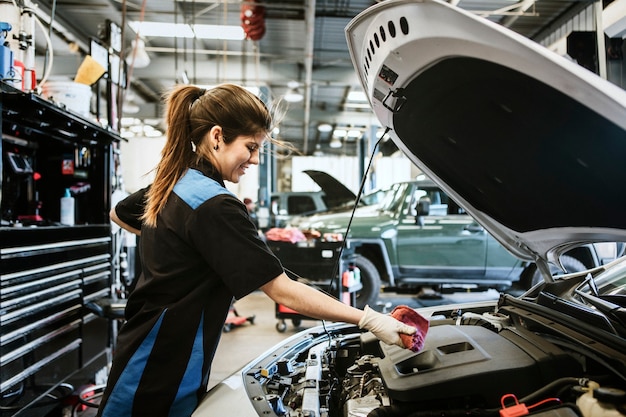 Junge Mechanikerin, die den Motorölmessstab abwischt