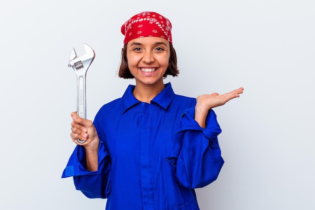 Junge mechanische Frau, die einen Schlüssel lokalisiert hält, der einen Kopienraum auf einer Handfläche zeigt und eine andere Hand auf Taille hält.