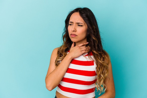 Junge mexikanische Frau, die an der blauen Wand isoliert wird, leidet unter Schmerzen im Hals aufgrund eines Virus oder einer Infektion.