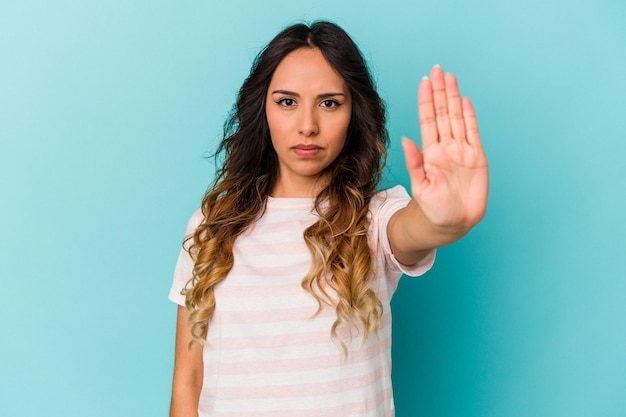 Junge mexikanische Frau isoliert auf blauem Hintergrund, die mit ausgestreckter Hand steht und Stoppschild zeigt und Sie verhindert.