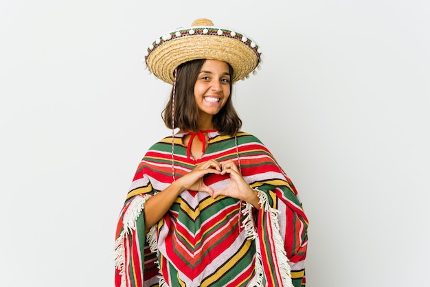 Foto junge mexikanische frau lokalisiert auf weißer wand lächelnd und zeigt eine herzform mit händen.