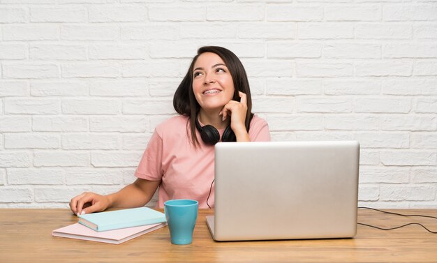 Junge mexikanische Frau mit einem Laptop oben lachend und schauend