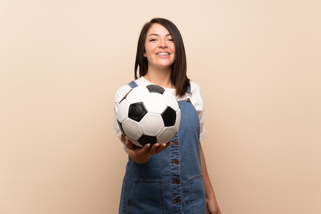 Junge mexikanische Frau über lokalisiertem Halten eines Fußballs