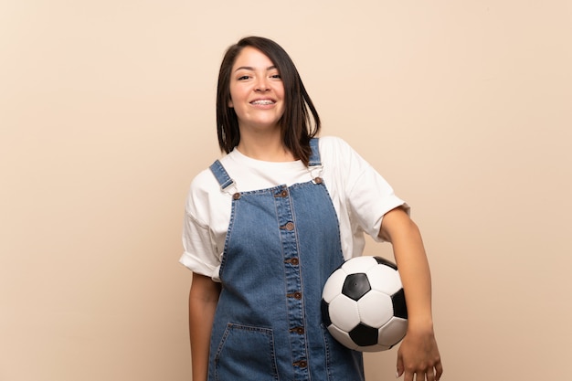 Junge mexikanische Frau über lokalisiertem Halten eines Fußballs