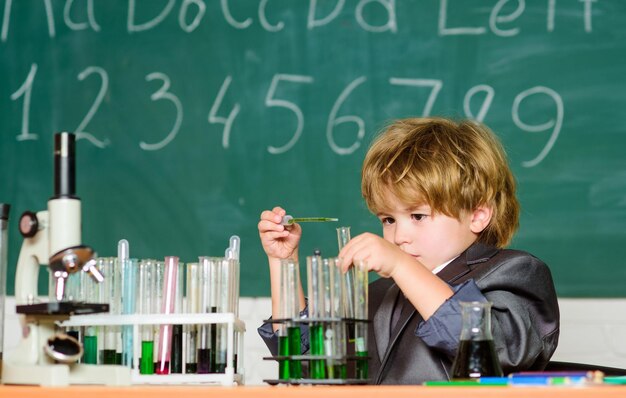 Junge Mikroskop und Reagenzgläser Schulklassenzimmer. Wissenskonzept. Faszinierendes Thema. Tag des Wissens. Kind studiert Biologie und Chemie. Basiswissen Grundschulbildung. Pädagogisches Experiment.