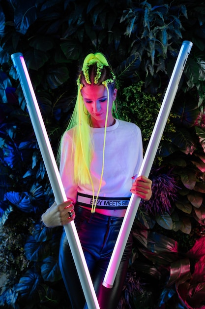Junge Millennial-Frau mit gelben Haaren in trendigen neonpinken und blauen Lichtern
