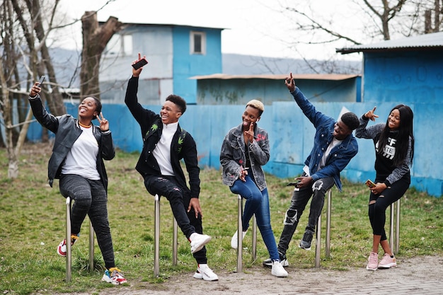 Junge Millennials afrikanische Freunde mit Mobiltelefonen Fröhliche schwarze Menschen, die gemeinsam Spaß haben Freundschaftskonzept der Generation Z
