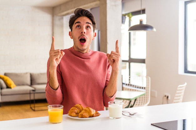 Junge Mischlinge, die morgens in einer Küche frühstücken und mit geöffnetem Mund nach oben zeigen.