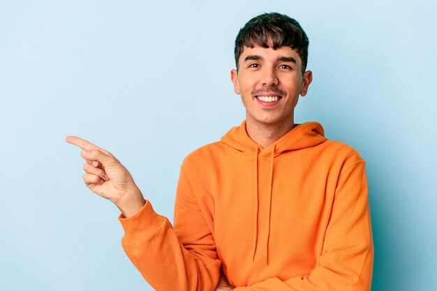 Junge Mischlinge isoliert auf blauem Hintergrund lächelnd fröhlich mit dem Zeigefinger weg zeigend.