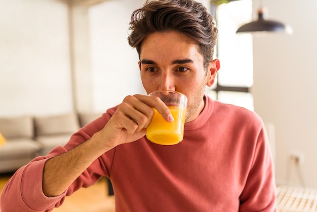 Junge Mischlinge trinken Orangensaft in seiner Küche