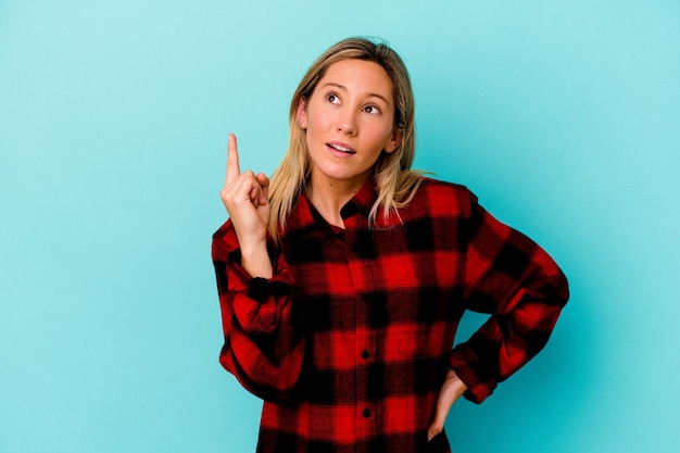 Junge Mischlingsfrau lokalisiert auf Blau mit einer Idee, Inspirationskonzept.