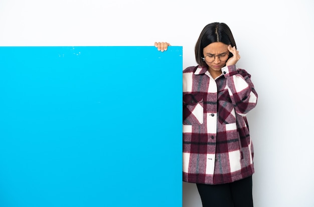 Junge Mischlingsfrau mit einem großen blauen Plakat isoliert auf weißem Hintergrund mit Kopfschmerzen