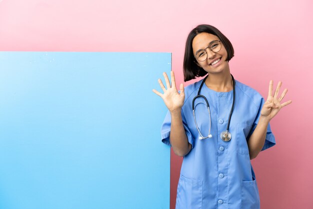 Junge Mischrassenchirurgin mit einem großen Banner über der isolierten Wand, die neun mit den Fingern zählt