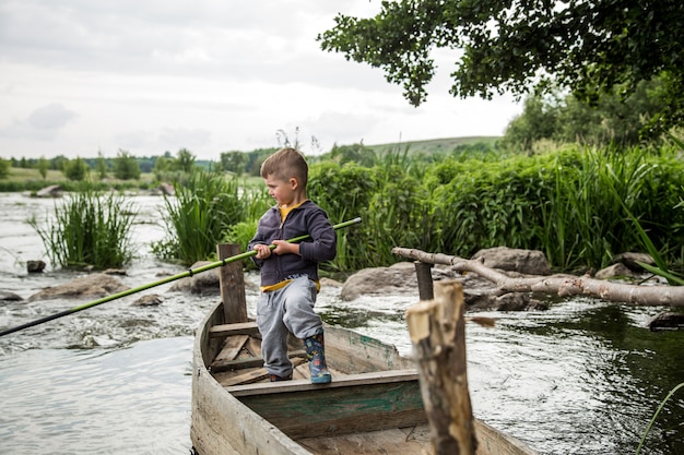 Junge mit Angelrutenfischen in einem Holzboot