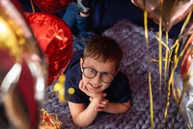 Junge mit Brille träumt auf dem Bett liegend