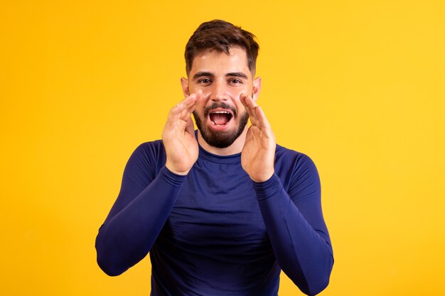 Junge mit den Händen auf dem Gesicht nahe dem Mund, der Förderung schreit.