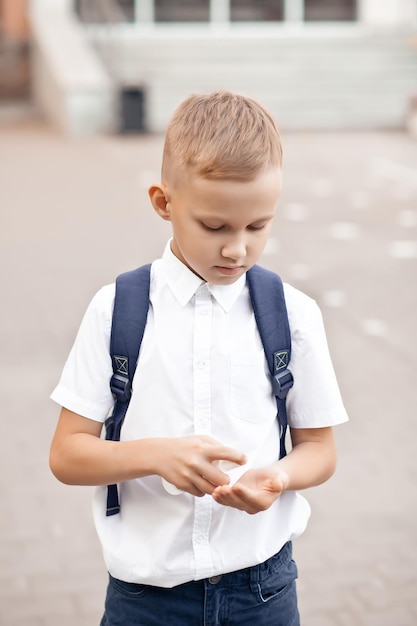 Junge mit Desinfektionsmittel oder Desinfektionsspray zur Desinfektion der Hände in der Schule. Coronavirus-Quarantäne, Pandemiepräventionskonzept.