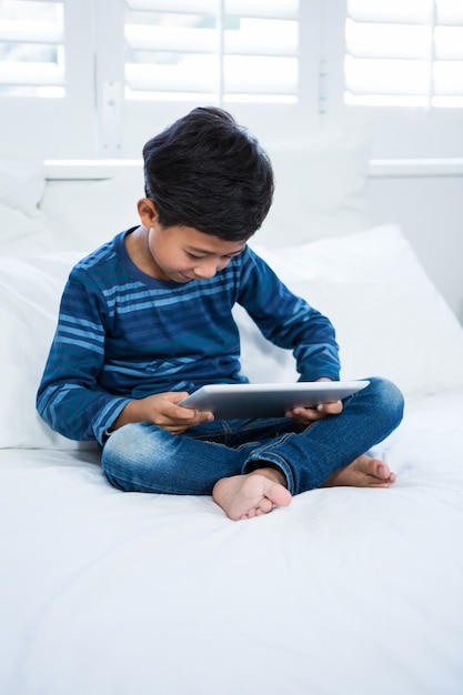 Junge mit digitaler Tablette beim Entspannen auf dem Bett