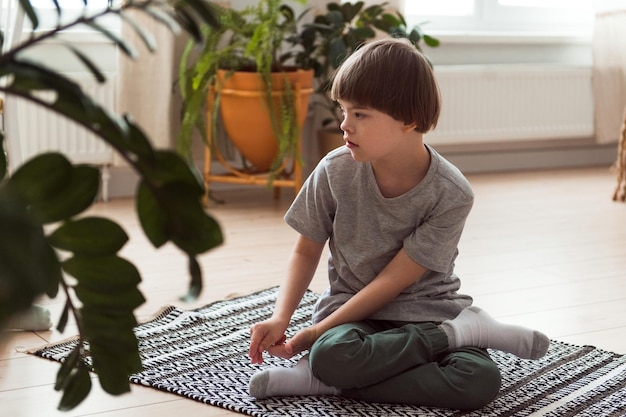 Junge mit Down-Syndrom sitzt allein auf dem Boden