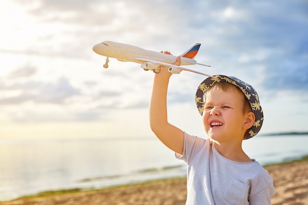 Junge mit einem Flugzeug in seinen Händen am Strand