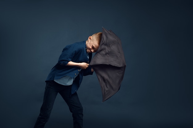 Junge mit einem verängstigten Gesicht hält Regenschirm im Studio