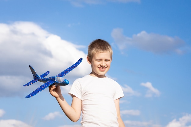 Junge mit Flugzeug auf Himmelhintergrund