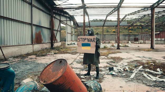 Junge mit Gasmaske hält Pappe mit Stop-War-Text in der Hand