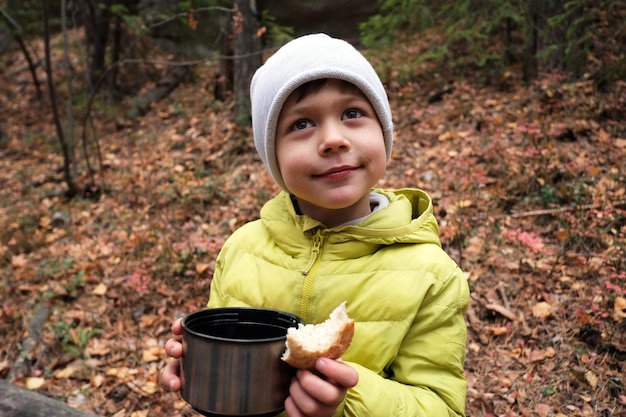 Junge mit heißem Getränk im Herbstwald